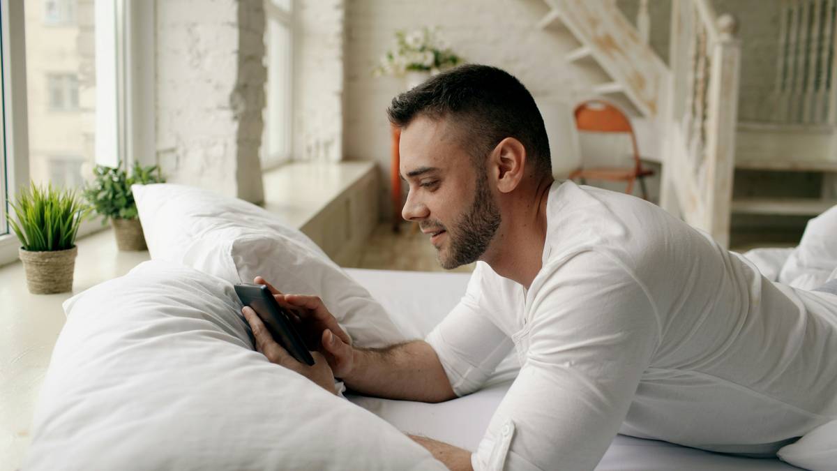 Person using smartphone to connect smart bed to bluetooth during nighttime setup